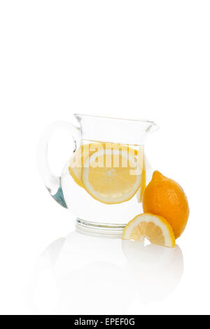 L'eau avec les tranches de citron dans un bocal en verre isolé sur fond blanc avec la réflexion. L'eau fraîche à boire. Banque D'Images