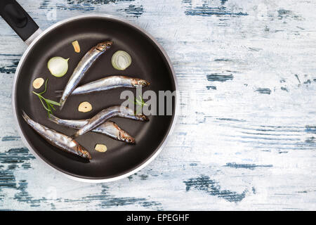 Manger des fruits de mer de la Méditerranée. Sardines fraîches sur pan noir sur blanc et bleu fond de bois texturé vue d'en haut. Fruits de mer Banque D'Images