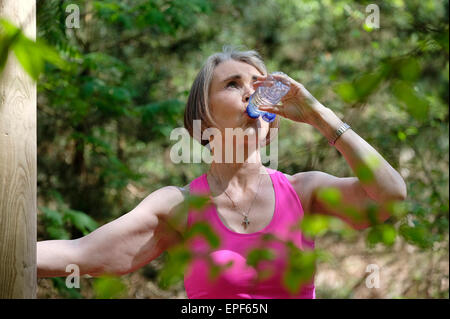 Senior woman l'eau potable de la forêt en bouteille Banque D'Images