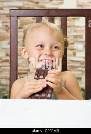 Little smiling girl avec du chocolat à la lumière prix Banque D'Images