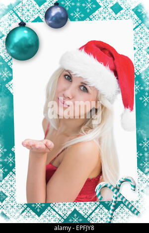 Image composite de woman wearing santa hat comme elle suce kiss Banque D'Images