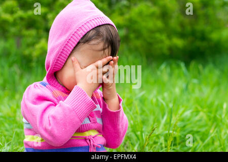 Petite fille joue à cache-cache et de se cacher face Banque D'Images