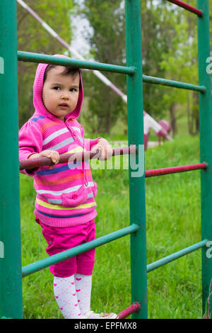 Happy little girl l'escalade sur le terrain de jeux extérieur Banque D'Images