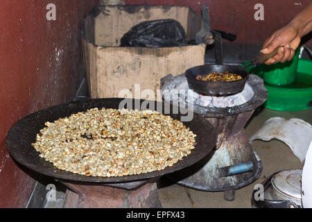 Personne éthiopien effectuant une cérémonie traditionnelle du café, la torréfaction des grains de café dans une casserole placée sur un feu de charbon. À l'intérieur. Banque D'Images