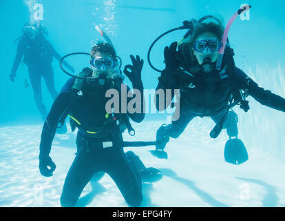 Amis de scuba training immergé dans une piscine à deux à l'appareil photo Banque D'Images