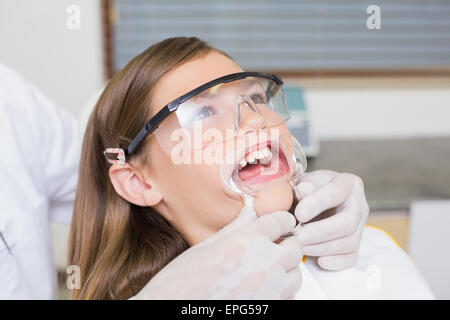 Dentiste mettant l'enrouleur sur la bouche petite fille Banque D'Images