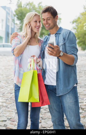 Hip young couple looking at smartphone sur shopping trip Banque D'Images