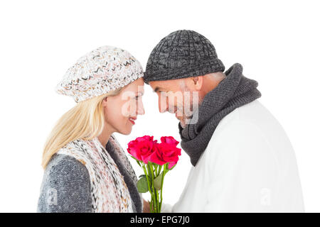 Smiling couple in winter fashion posant avec des roses Banque D'Images