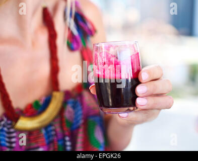 Femme tenant un verre de jus de betteraves rouges Banque D'Images