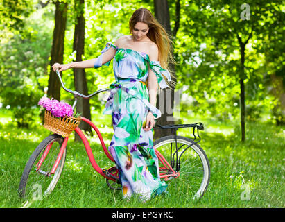 Belle blonde femme portant une jolie robe s'amusant en parc avec location d'un beau panier rempli de pivoine Banque D'Images