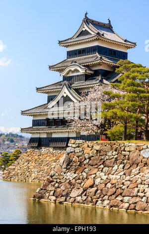 Le château japonais de Mastumoto en plâtre blanc avec des planches de temps noires, de l'autre côté de la lune contre un ciel bleu. Une attraction touristique populaire. Banque D'Images