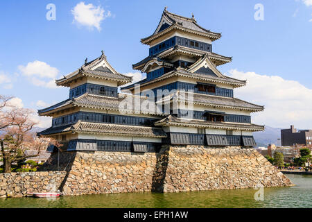 Le château japonais de Mastumoto en plâtre blanc avec des planches de temps noires, de l'autre côté de la lune contre un ciel bleu. Une attraction touristique populaire. Banque D'Images