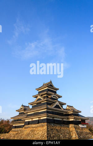 Une attraction touristique populaire, le donjon du château de Matsumoto au Japon dans l'heure d'or de l'après-midi juste avant le coucher du soleil avec un fond bleu ciel. Banque D'Images