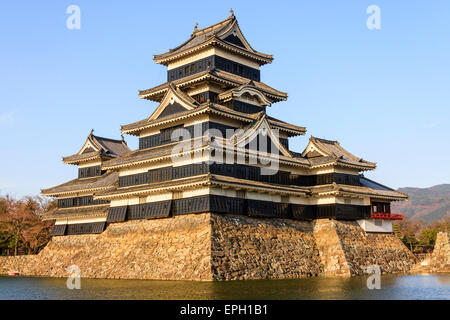 Une attraction touristique populaire, le donjon du château de Matsumoto au Japon dans l'heure d'or de l'après-midi juste avant le coucher du soleil avec un fond bleu ciel. Banque D'Images