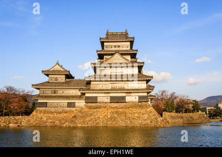 Une attraction touristique populaire, le donjon du château de Matsumoto au Japon dans l'heure d'or de l'après-midi juste avant le coucher du soleil avec un fond bleu ciel. Banque D'Images