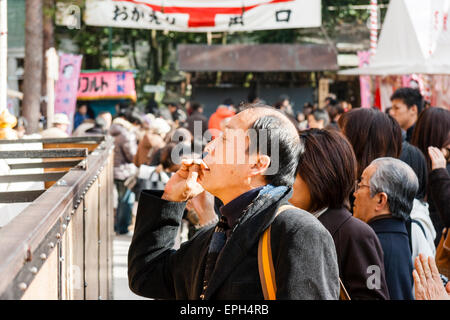 Nouvelle année au Japon. Homme jetant de la monnaie dans la grande boîte de collecte devant le hall principal du sanctuaire Yasaka à Kyoto pendant sa visite à Hatsumode. Banque D'Images