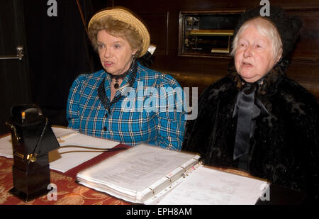 Deux femmes âgées habillé en costume victorien à l'auditoire de lecture pour accompagner les images projetées à un spectacle de lanterne magique... Banque D'Images