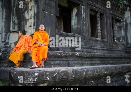 SIEM REAP, Cambodge - 30 octobre 2014 : Paire de novice moines bouddhistes en robe safran s'asseoir à l'extérieur d'un temple d'Angkor Wat. Banque D'Images