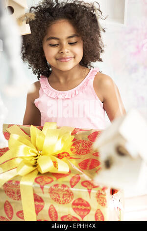 Petite fille mignonne à regarder le cadeau d'anniversaire Banque D'Images