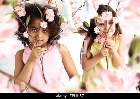 Deux petites filles se cachant derrière les branches Banque D'Images