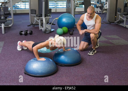 Male trainer assisting woman avec push up at gym Banque D'Images