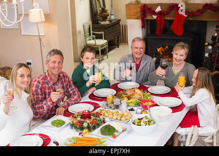 Smiling family toasting à l'appareil photo pendant le dîner de Noël Banque D'Images