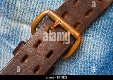 Ceinture en cuir serré sur fond de jeans Banque D'Images