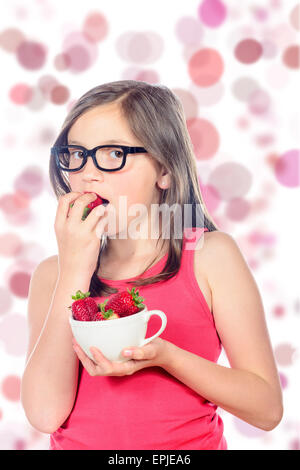 Une petite fille vêtue de rose de manger une fraise Banque D'Images