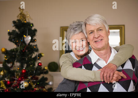 Senior couple smiling à côté de leur arbre de Noël Banque D'Images