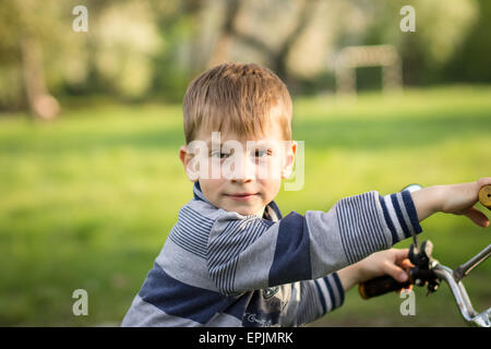 Funny boy a in parc d'été avec son vélo. Banque D'Images