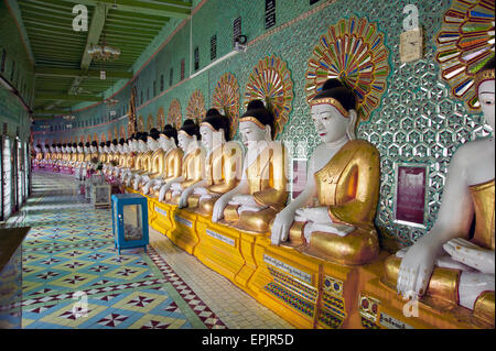 Longue rangée de Bouddhas en pierre peint contre un mur du temple vert dans l'ancienne capitale du Myanmar Sagaing Banque D'Images