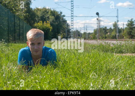 Jeune homme en bleu allongé sur l'herbe verte Banque D'Images