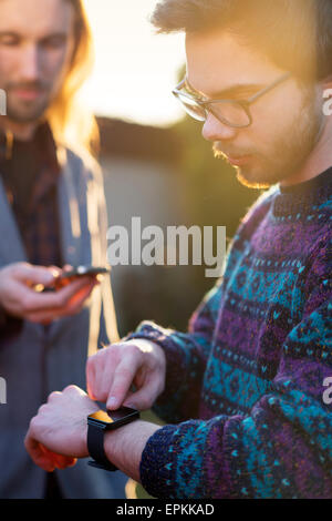 Deux hipsters avec smartwatch et smartphone Banque D'Images