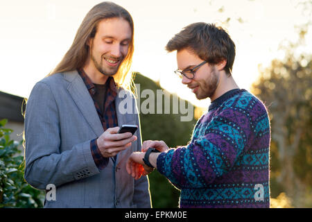 Deux hipsters avec smartwatch et smartphone Banque D'Images