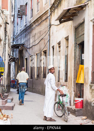 Les gens marcher sur l'une des rues étroites dans la vieille partie de Stone Town, Zanzibar en Afrique de l'Est. Orientation horizontale. Banque D'Images