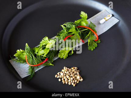 Représentation d'un humoristique inspiré de chanvre avec repas, les graines de chanvre, coriandre, rizlas sur plaque noire. Banque D'Images