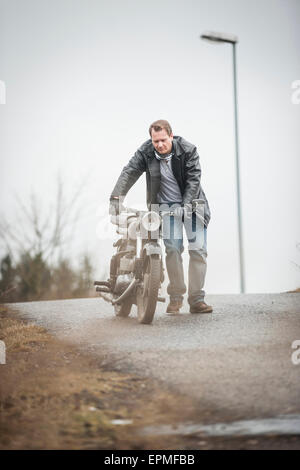 Homme avec veste en cuir vintage cyclomoteur poussant Banque D'Images