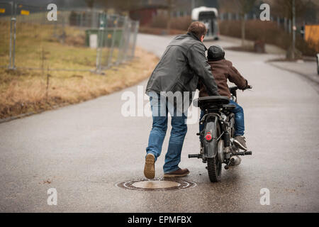 Père et fils la conduite avec vintage cyclomoteur Banque D'Images