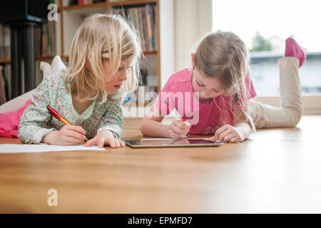 Deux soeurs avec tablette numérique et de feuilles de papier sur marbre Banque D'Images