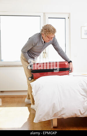 Man packing suitcase dans la chambre Banque D'Images