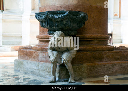 La figure accroupie sous le bénitier dans l'église de Santa Anastasia a été sculpté par Paolo Orefice. Il est connu comme "Pasquino" Banque D'Images