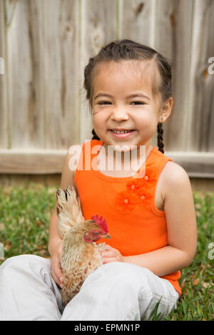 Une jeune fille tenant un poulet. Banque D'Images