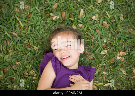 Un enfant couché sur son dos sur l'herbe. Banque D'Images