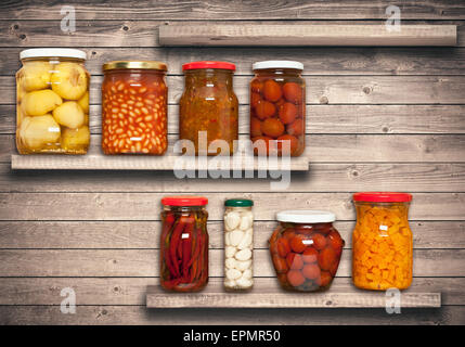 Conserves de carottes, tomates, Ail, piment, les haricots sur une étagère près d'un mur en bois brun Banque D'Images