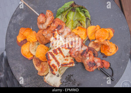 Une partie de la brochette de porc bacon, pommes de terre et pommes de terre frites, salade romaine grillée et fromage Halloumi Banque D'Images