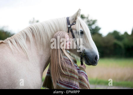 Une jeune femme debout à côté d'un cheval palomino Banque D'Images