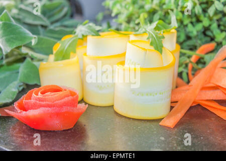 Rouleaux de courgettes jaunes, près de fines herbes et une fleur de tomate Banque D'Images