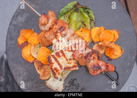 Une partie de la brochette de porc bacon, pommes de terre et pommes de terre frites, salade romaine grillée et fromage Halloumi Banque D'Images