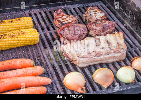 Les grillades de viandes et de légumes, y compris le maïs, carottes, oignons, porc cutlass, pavé de veau et porc Banque D'Images