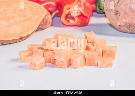 Une pile de dés de pommes de terre orange, en face de légumes Banque D'Images